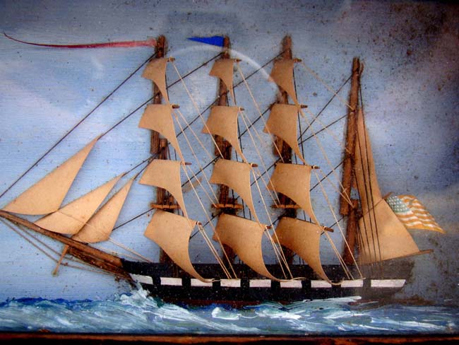 A charming miniature 19th century shadow box diorama of a four-masted ship nearing a lighthouse.